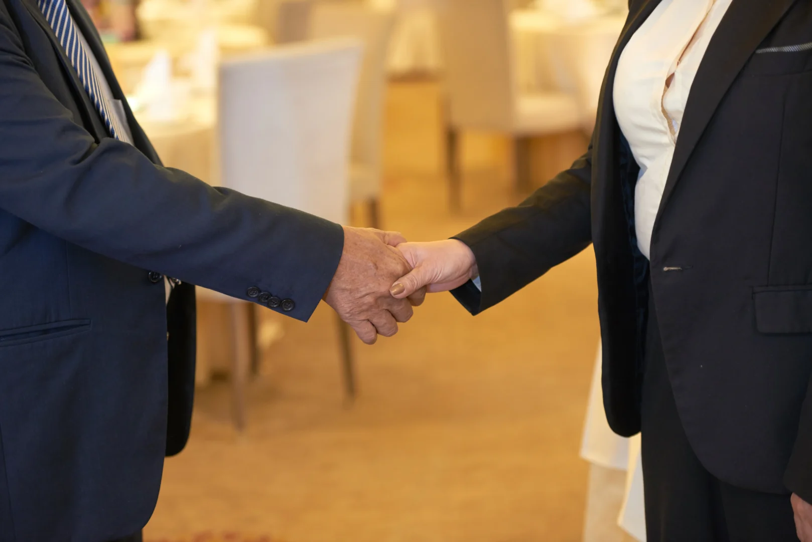 Zwei Personen in Businesskleidung geben sich zur Begrüßung die Hand – Symbol für Vertrauen und partnerschaftliche Zusammenarbeit bei Maisenbacher.